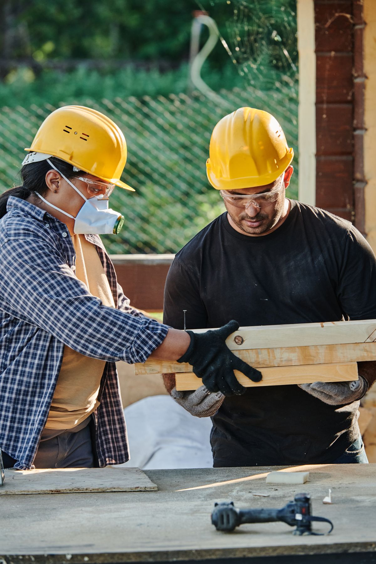 Dos operarios de New House revisando una pieza de madera en la obra